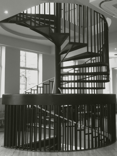 black and white photograph of a spiral staircase viewed from the side with metal uprights